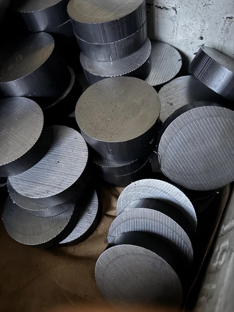 Nahaufnahme eines Stapels runder Metallstücke mit bearbeiteter Oberfläche. Die Stücke liegen dicht aneinander und füllen den Rahmen.