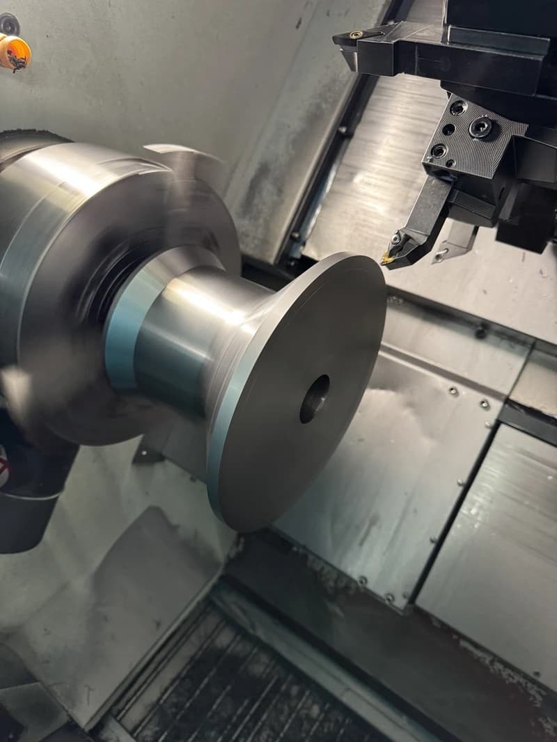 Ein rotierendes Metallteil wird in einer Drehmaschine bearbeitet. Das Werkzeug nähert sich dem Werkstück, um es zu formen.