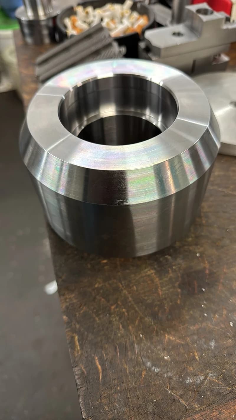 Nahaufnahme eines glänzenden Metallrings, der auf einer Werkbank steht. Der Ring hat eine glatte Oberfläche und reflektiert das Licht.